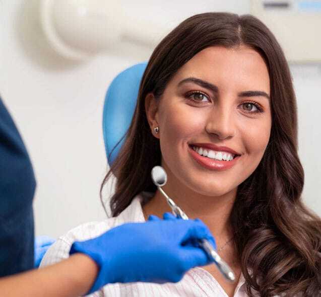 Smiling dental patient in blue chair during first visit consultation with dentist.