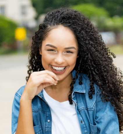 Smiling young woman with healthy teeth wearing denim shirt in dental practice setting.