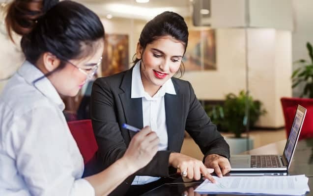 Two dental professionals reviewing orthodontic treatment documents together at an office desk.