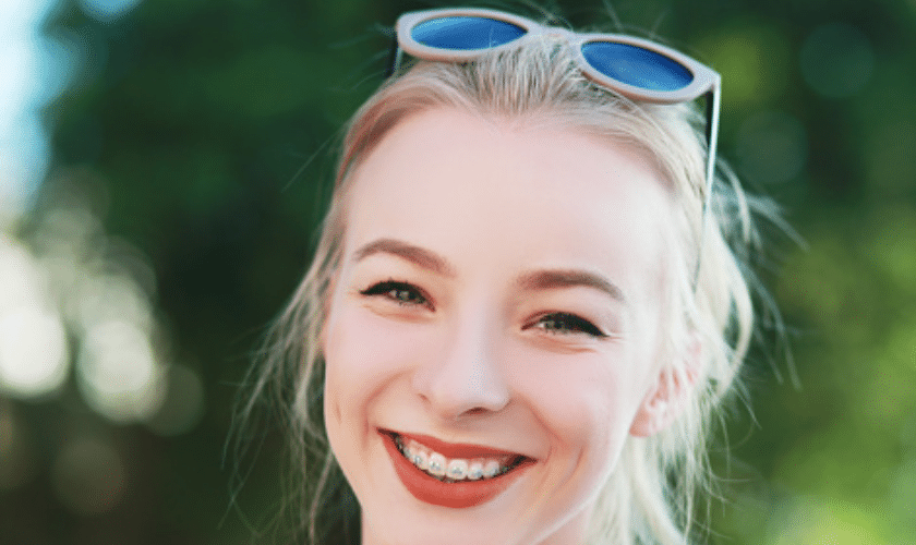 Young woman with braces smiling, demonstrating successful orthodontic treatment results.