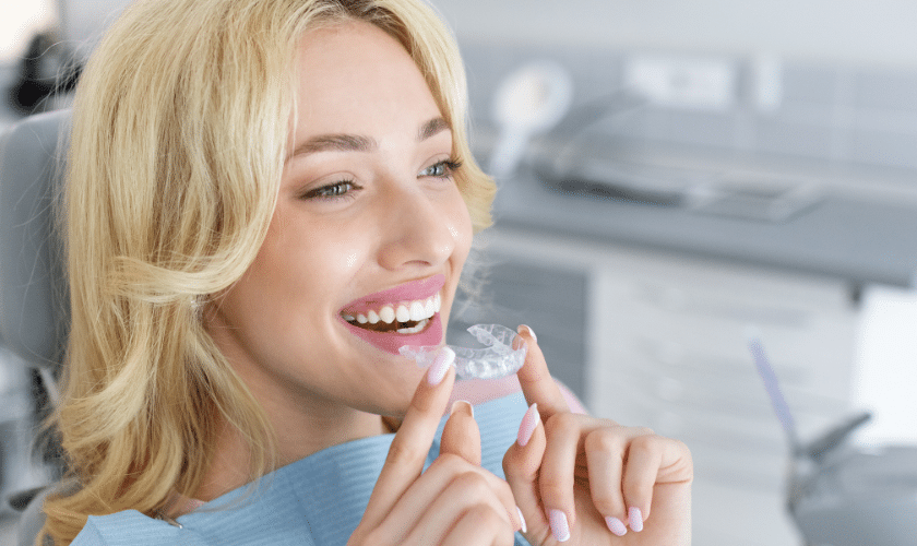 Young woman inserting clear orthodontic aligner to improve her smile and bite.
