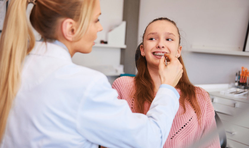 Dentist examining young patient's teeth during orthodontic consultation in Woodbury office.