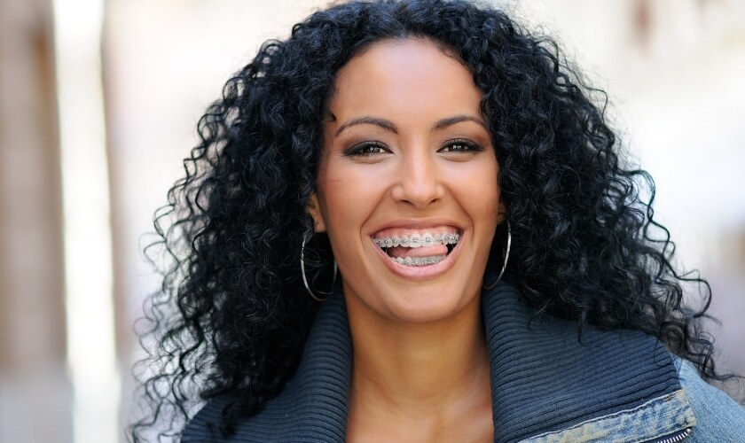Smiling woman with dental braces showing healthy teeth and confident expression.