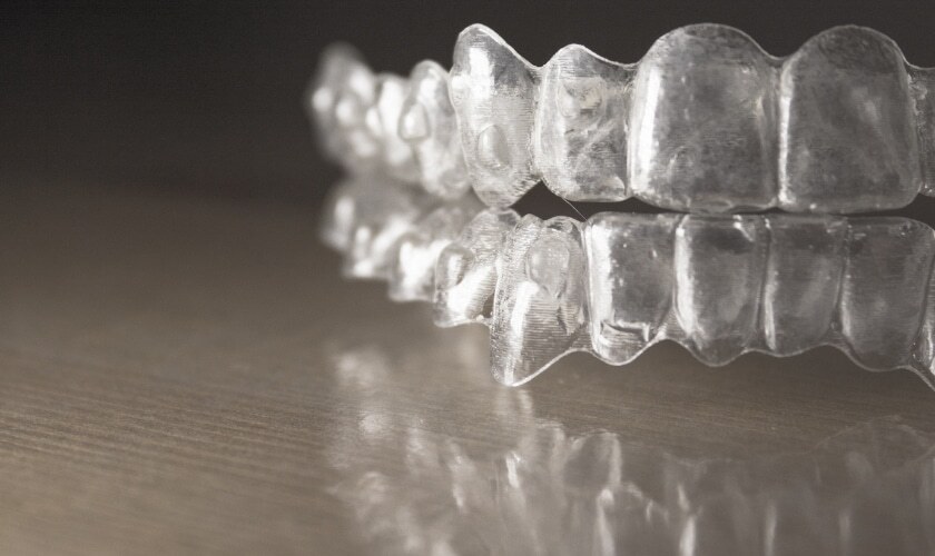 Clear Invisalign aligners displayed in pairs showing upper and lower trays for orthodontic treatment.