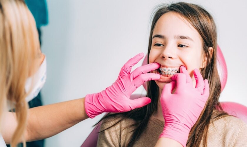 Orthodontist fitting clear braces aligner on young patient's teeth during treatment.
