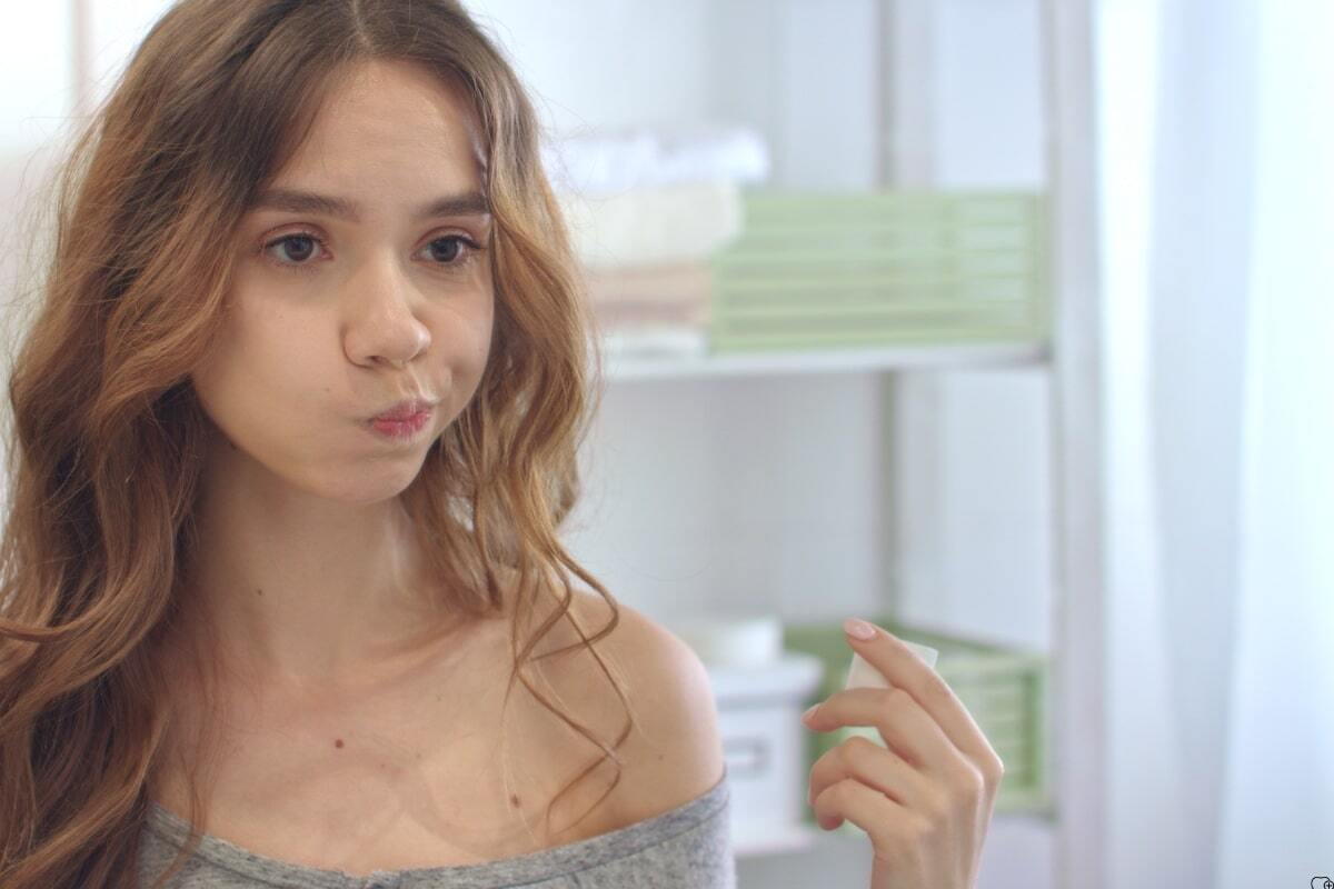 Young woman with wavy brown hair considering fluoride rinse for orthodontic care.