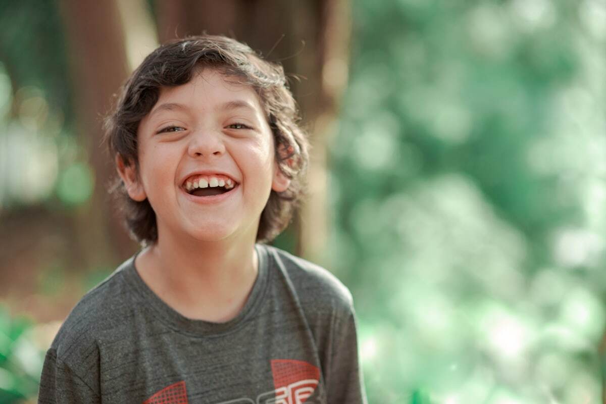 Happy child with a bright smile wearing a gray t-shirt outdoors.