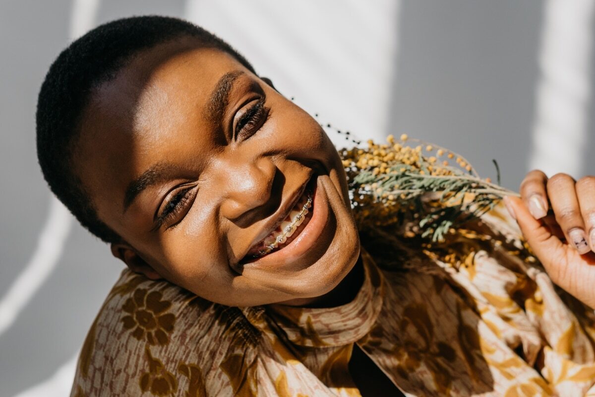 Woman smiling with hand near face, showing healthy teeth and positive dental care attitude.