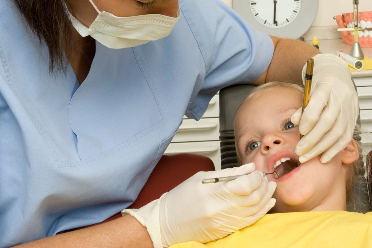 Pediatric dentist examining child's teeth during dental consultation in Woodbury office.