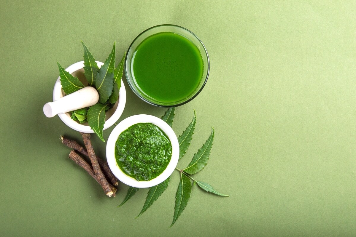 Neem leaf paste and extract in white bowls with fresh neem leaves for treating gum problems.