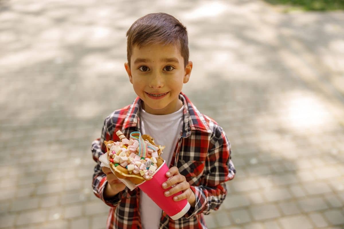 Young boy in plaid shirt holding colorful candy cone, illustrating holiday treats to enjoy mindfully.
