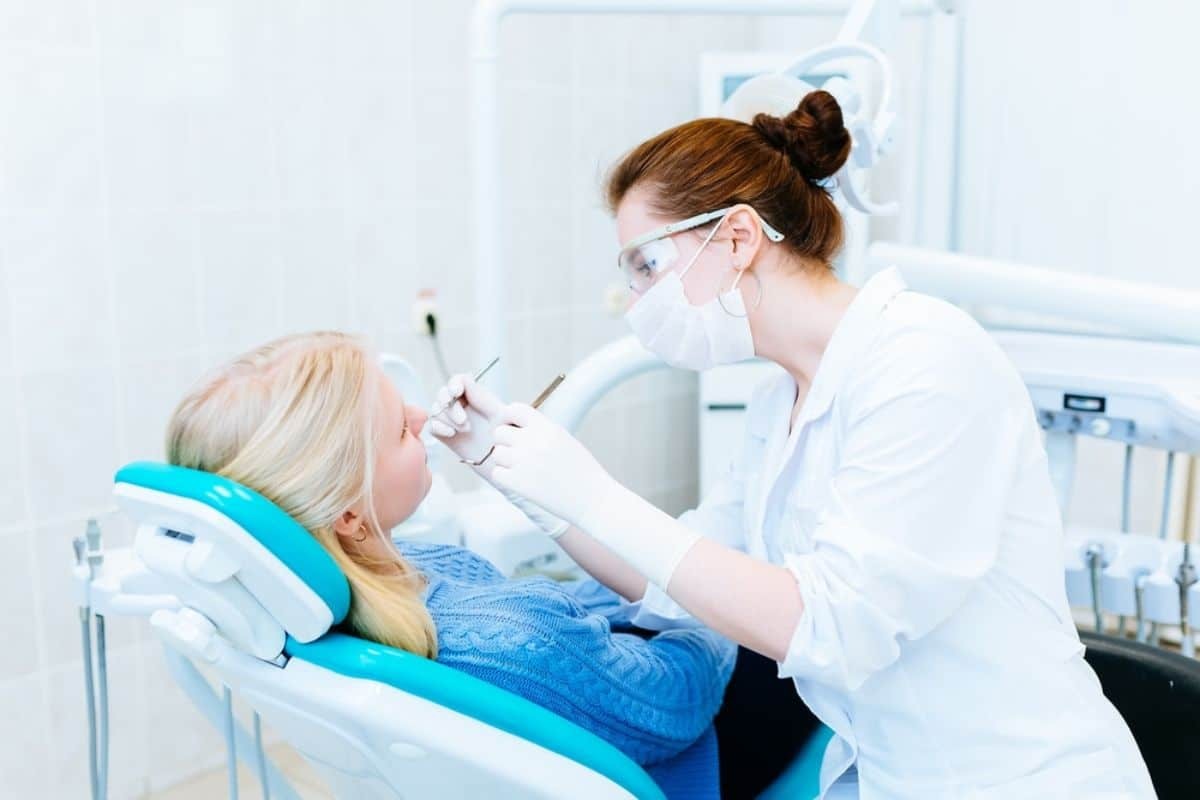 Dental hygienist examining a patient's teeth during an orthodontic appointment.