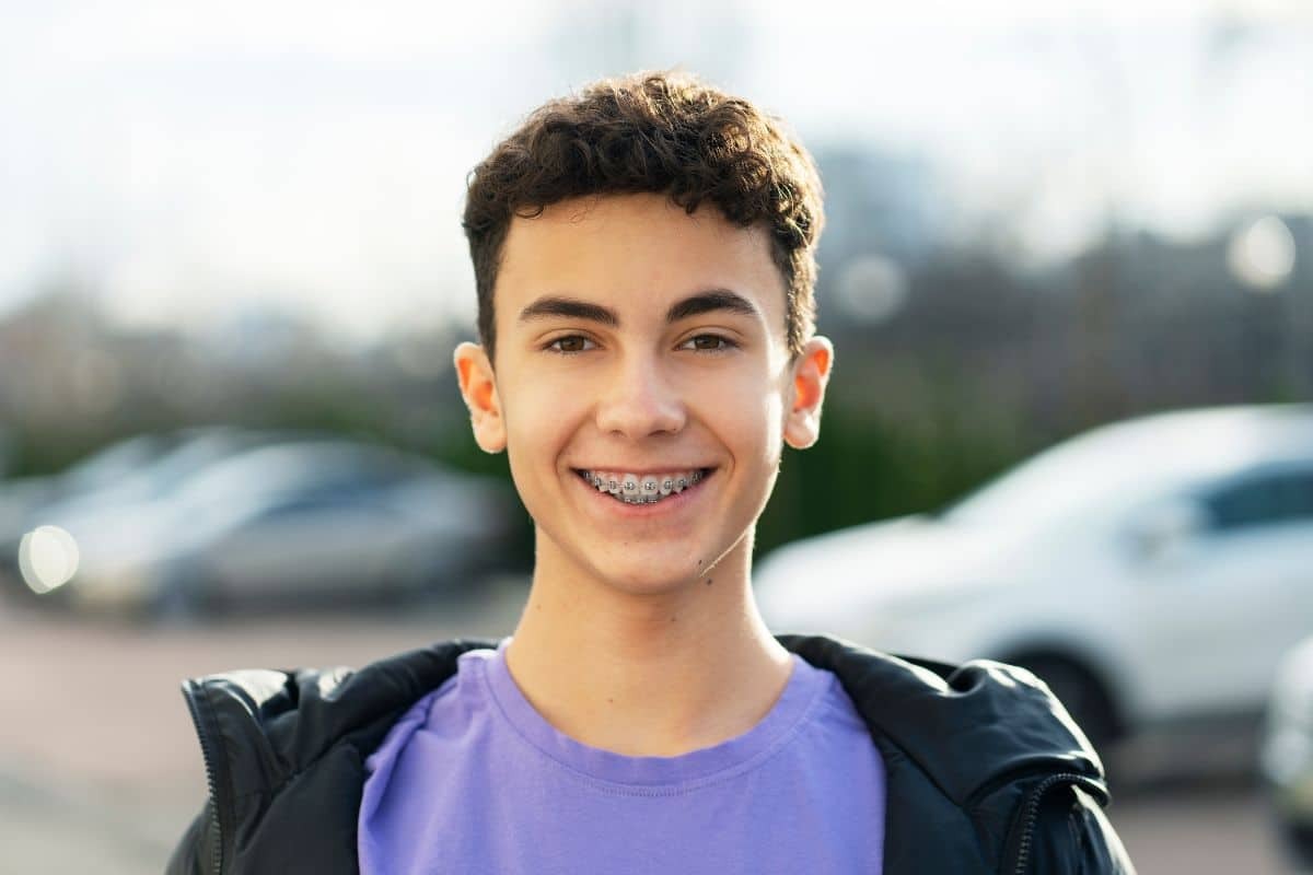 Smiling teen wearing braces demonstrates the confidence gained from orthodontic treatment.