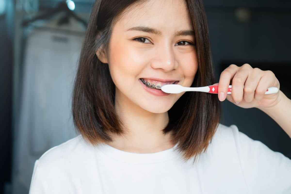 Young woman brushing teeth with braces using proper technique for orthodontic care.