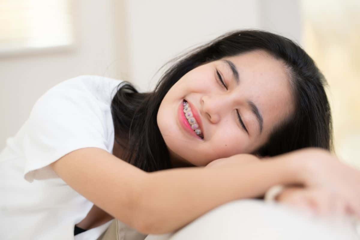 Young girl with braces smiling peacefully, demonstrating improved breathing and sleep quality from orthodontic treatment.