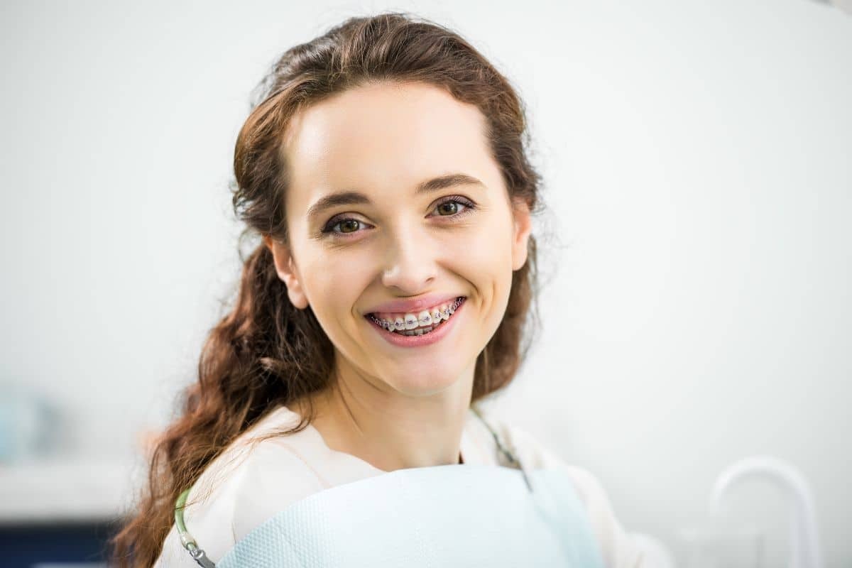 Young woman with braces smiling confidently at orthodontic practice in Woodbury, MN.