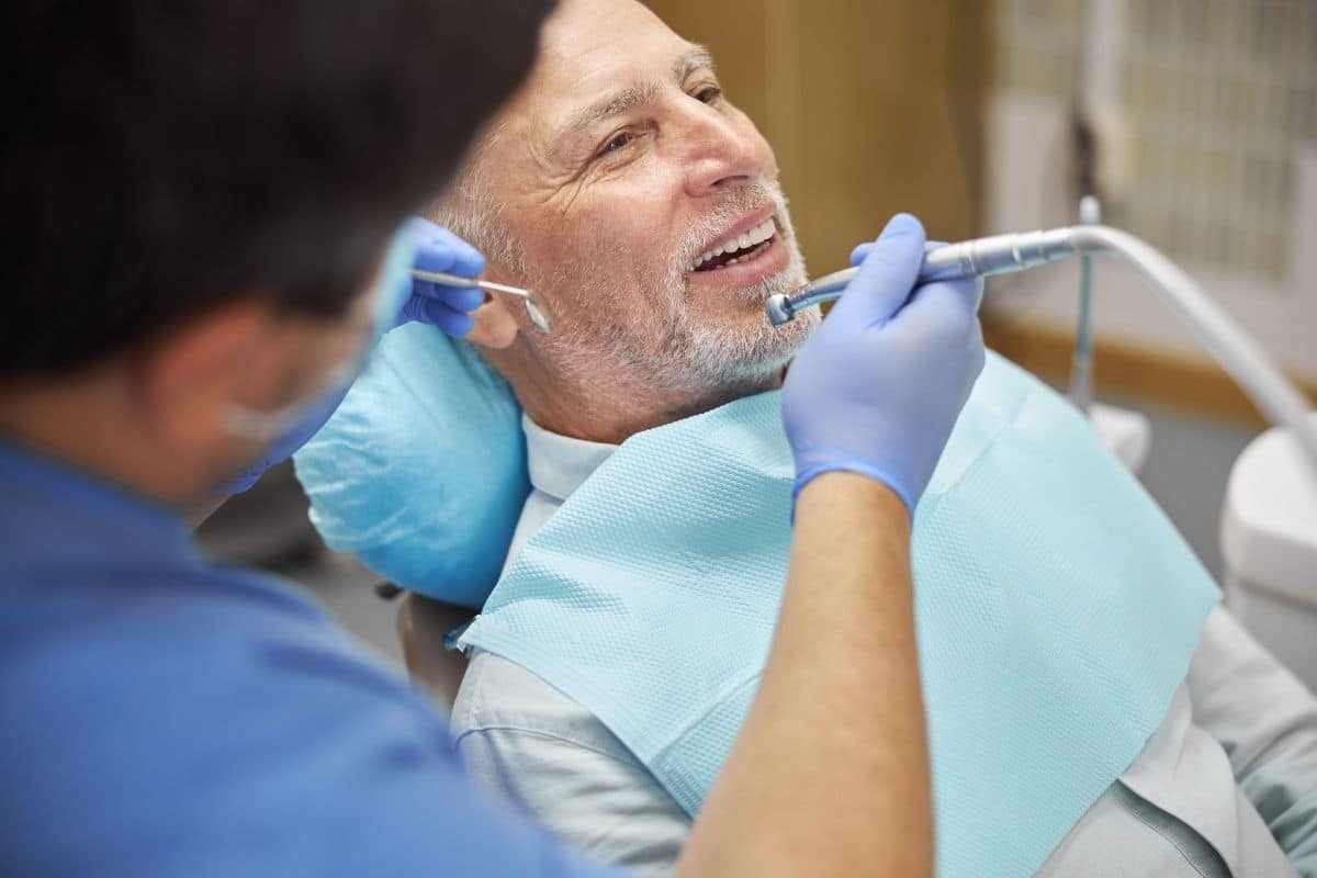 Mature male patient smiling during dental examination with dentist in Woodbury, MN.