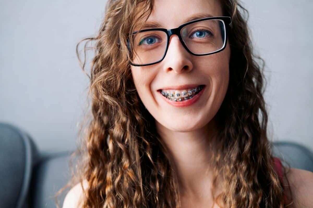 Young woman with braces smiling confidently, showcasing dental treatment results.