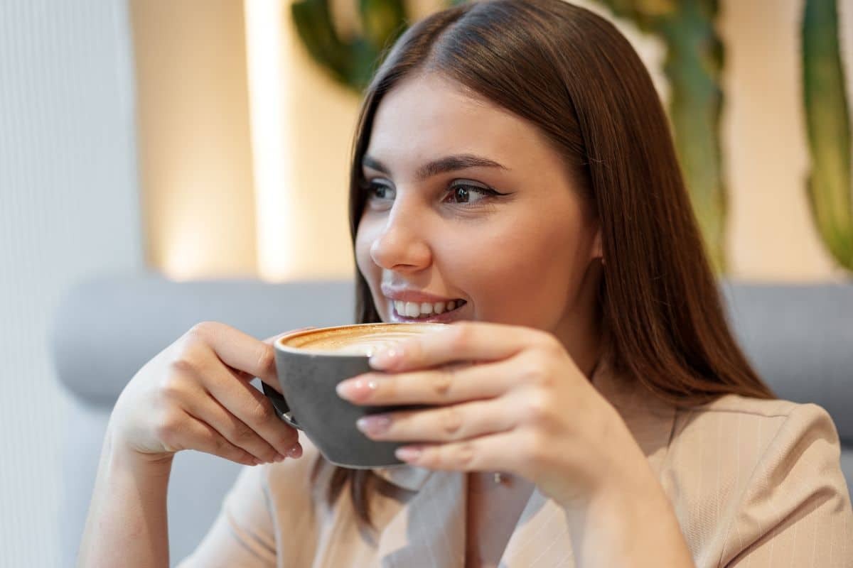 Woman enjoying coffee while wearing Invisalign aligners at a dental practice in Woodbury, Minnesota.