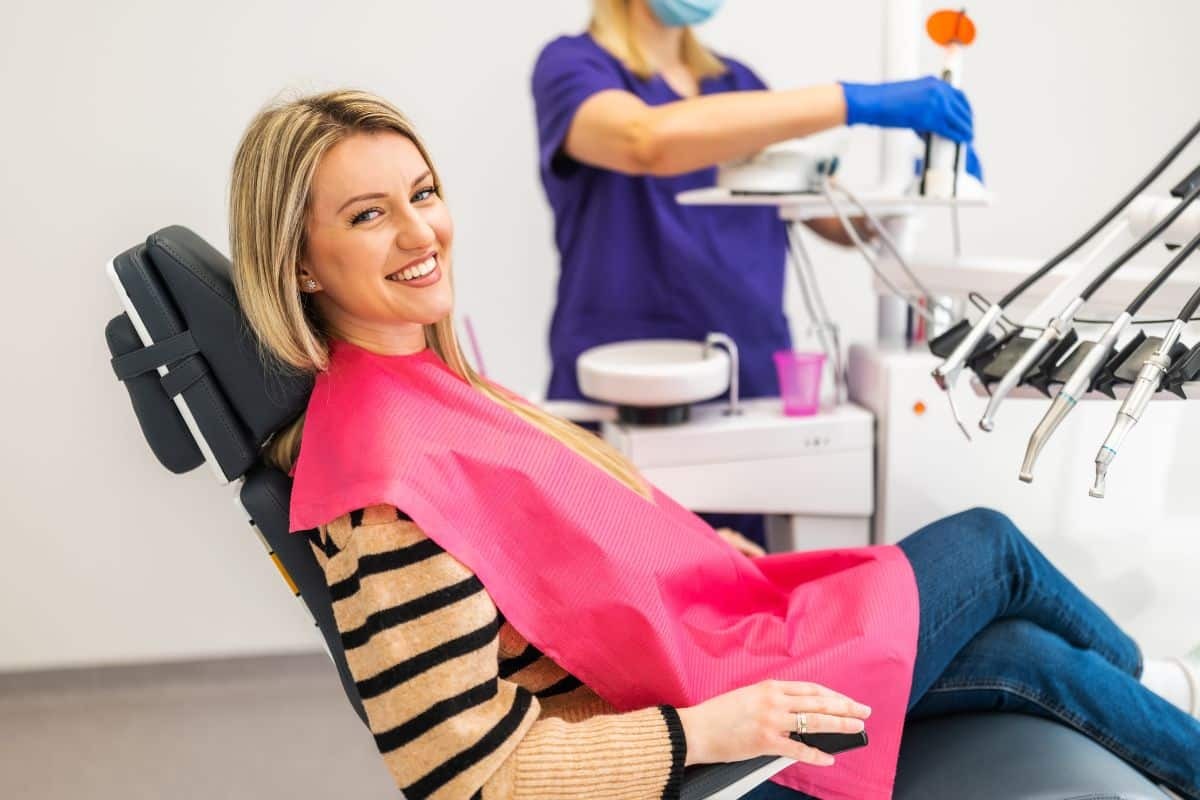 Smiling patient in dental chair during orthodontic consultation with dentist preparing treatment.