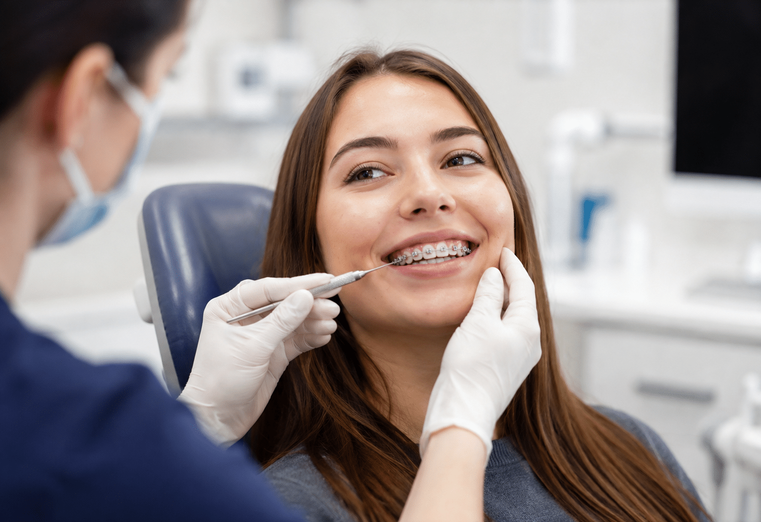 Orthodontist examining patient's braces during dental checkup in treatment room.